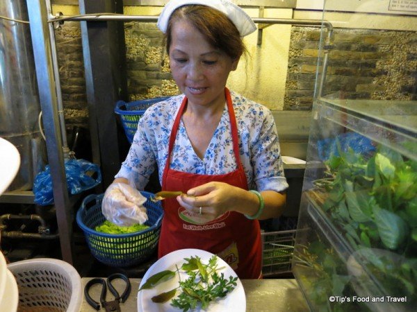A lady who prepares vegetable dish to every customer.
